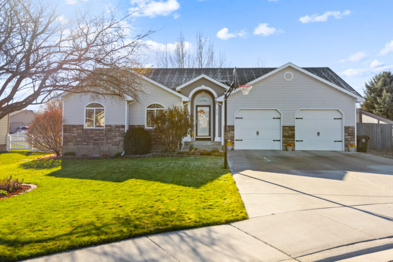 A residential home with a grassy area and tree in front.