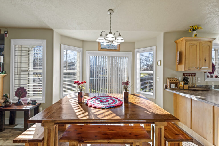 A dining room with a window and door, with sunlight entering the room through the windows