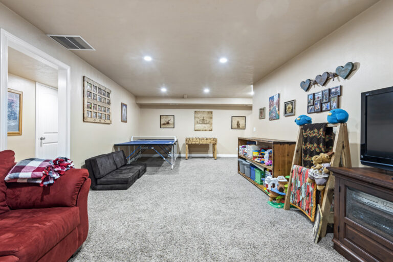 A home interior featuring wall frames, a red sofa, wooden shelves, TV and various items